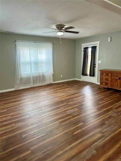 Unfurnished living room with wood finished floors, a ceiling fan, and a textured ceiling