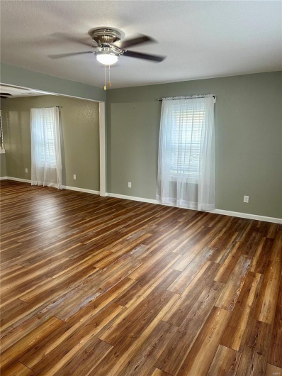 Unfurnished room featuring ceiling fan, wood finished floors, and baseboards