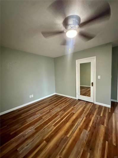 Unfurnished room with baseboards, a ceiling fan, and dark wood finished floors
