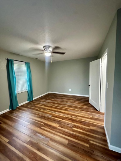 Unfurnished room featuring hardwood / wood-style floors, baseboards, and a ceiling fan