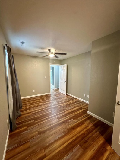 Spare room with baseboards, visible vents, ceiling fan, and dark wood-style flooring