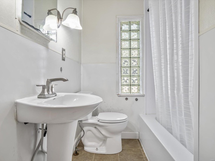 Bathroom with tile patterned floors, shower / tub combo, and toilet