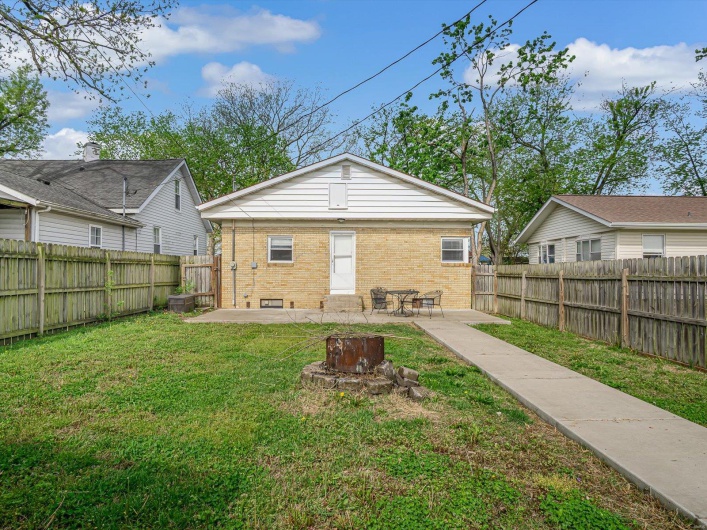 Rear view of house with a patio, central AC unit, a yard, a fenced backyard, and brick siding