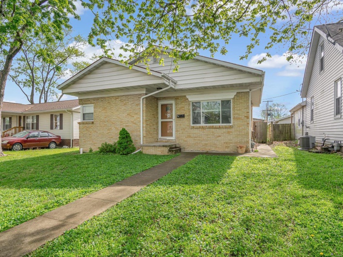 View of front facade with brick siding, fence, and a front yard