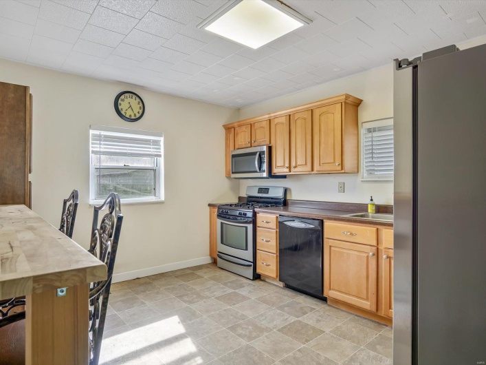 Kitchen featuring baseboards, stainless steel appliances, dark countertops, and a sink
