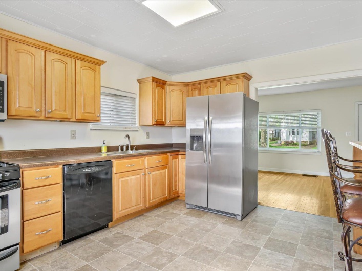 Kitchen featuring stove, stainless steel fridge with ice dispenser, dark countertops, dishwasher, and a sink