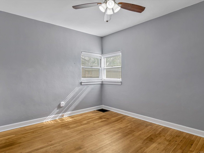 Empty room featuring wood finished floors, a ceiling fan, and baseboards