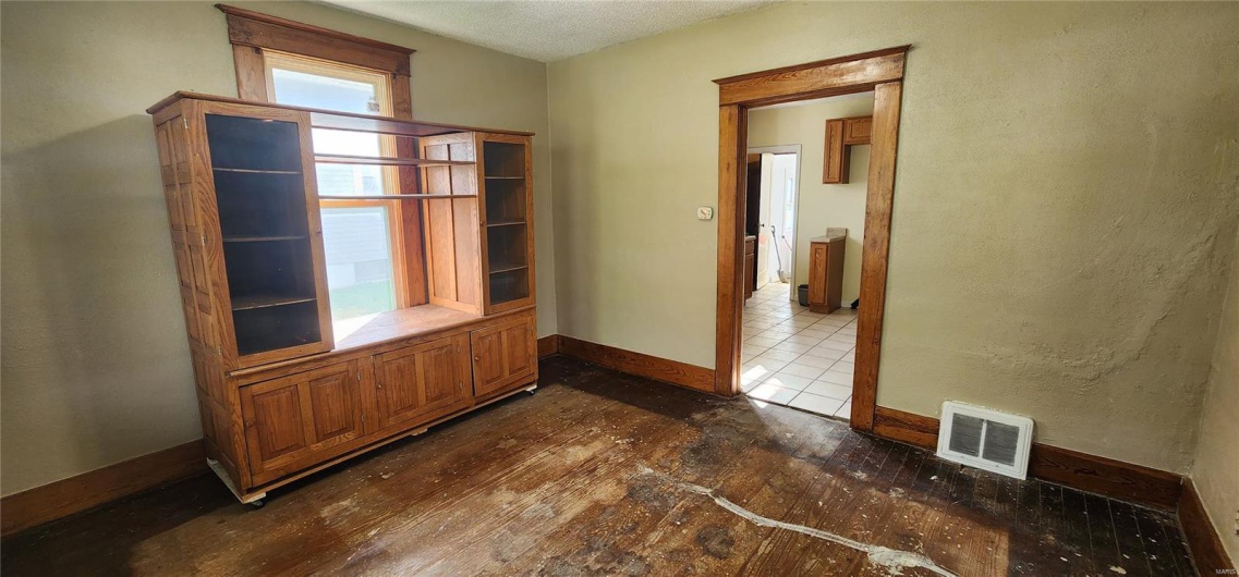 Empty room featuring dark wood-style floors, visible vents, and baseboards