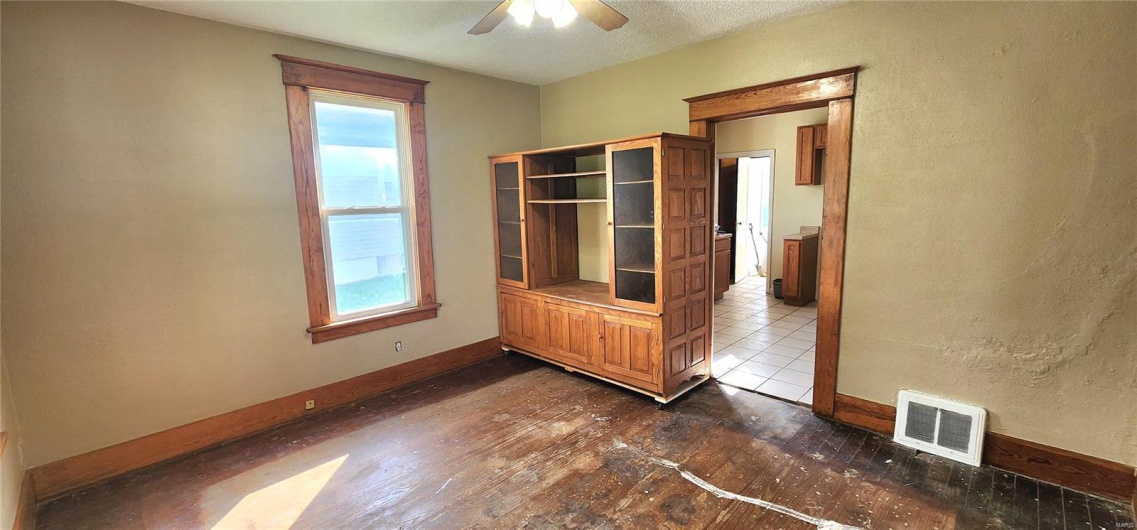 Empty room featuring dark wood-style floors, visible vents, ceiling fan, and baseboards