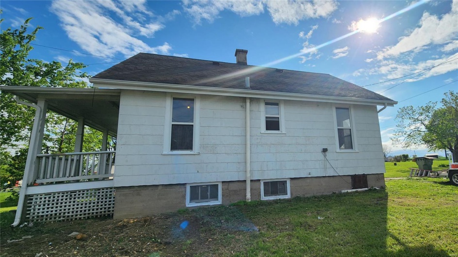 Rear view of property featuring a chimney, a shingled roof, and a yard