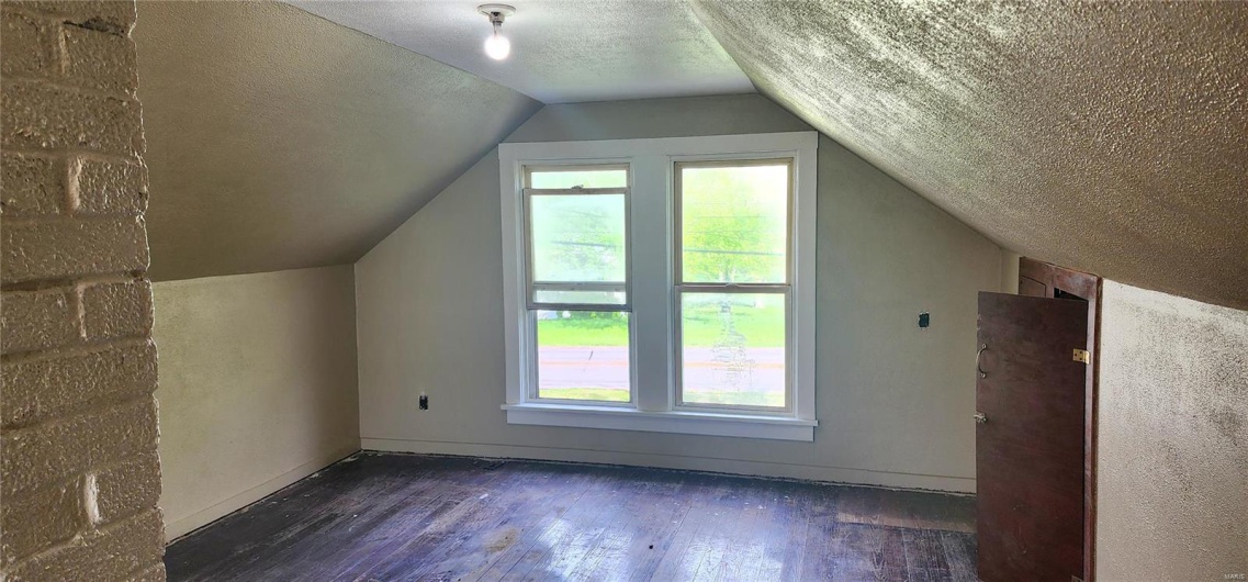 Bonus room featuring plenty of natural light, a textured ceiling, wood-type flooring, and vaulted ceiling