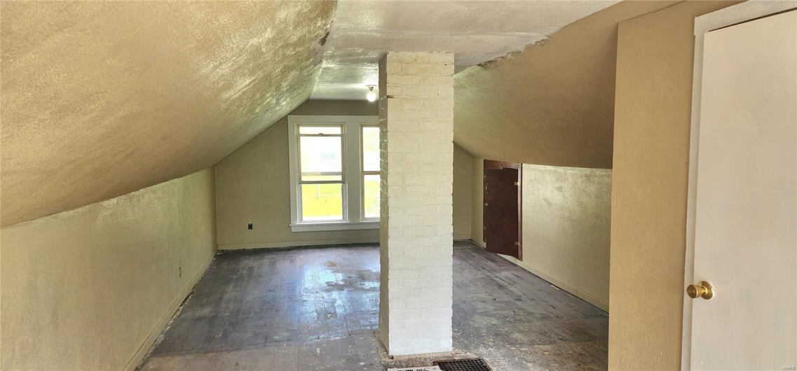 Additional living space with lofted ceiling, a textured ceiling, a textured wall, baseboards, and decorative columns