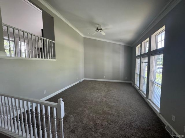 Carpeted empty room featuring crown molding, baseboards, ceiling fan, and visible vents