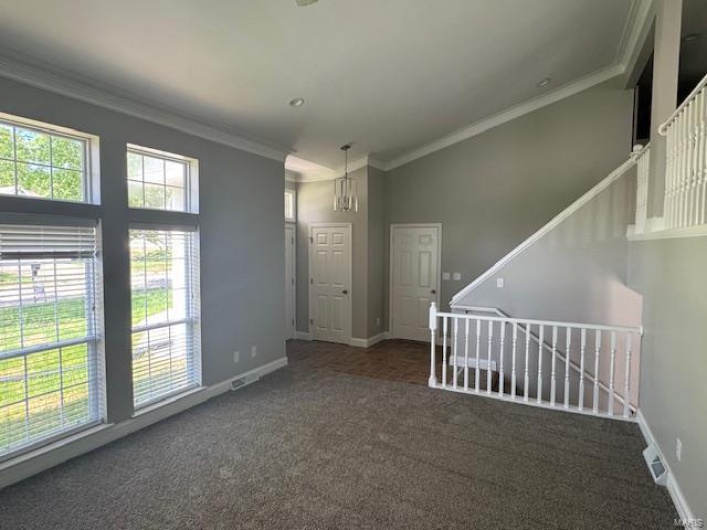 Carpeted spare room with baseboards, visible vents, and ornamental molding