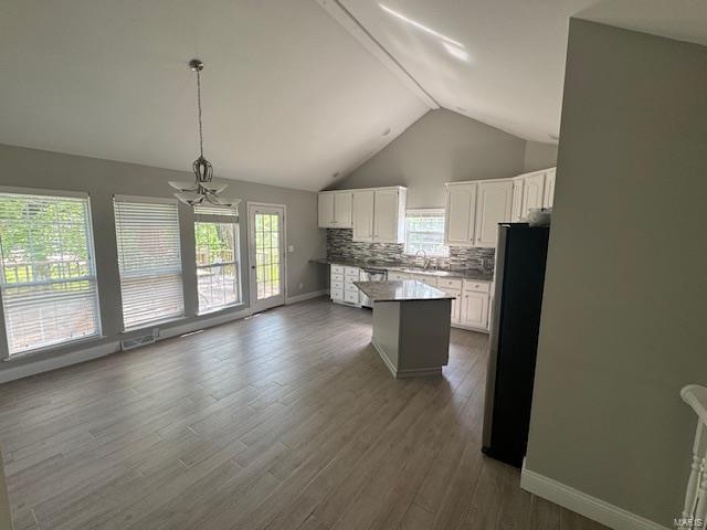 Kitchen featuring tasteful backsplash, a sink, white cabinets, freestanding refrigerator, and lofted ceiling