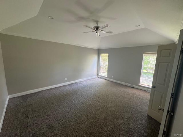 Carpeted spare room with baseboards, ceiling fan, vaulted ceiling, and a healthy amount of sunlight