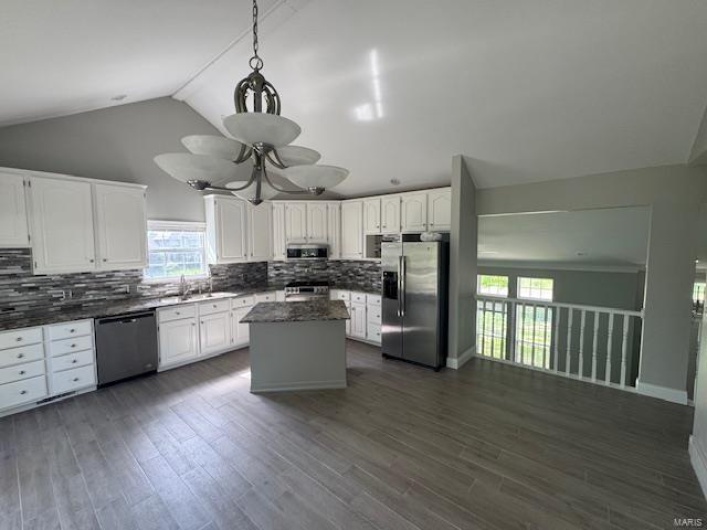 Kitchen with white cabinetry, tasteful backsplash, a sink, vaulted ceiling, and stainless steel appliances