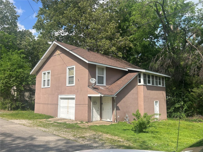 View of front facade with stucco siding, roof with shingles, and a front lawn
