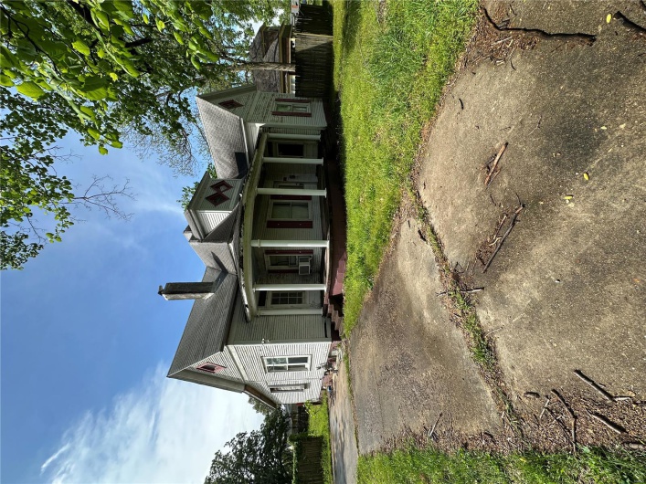 View of front of property featuring a chimney, a porch, fence, cooling unit, and a front yard