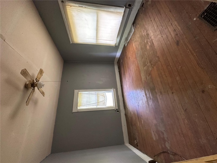 Empty room featuring a textured ceiling, hardwood / wood-style floors, a ceiling fan, and baseboards