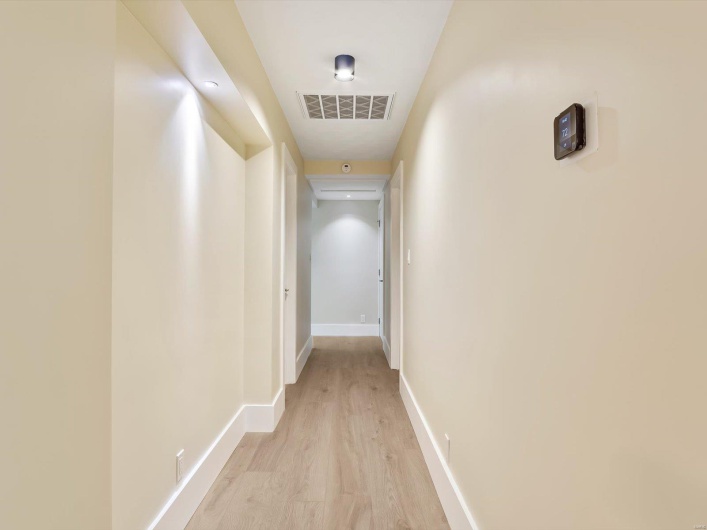 Hallway featuring light wood finished floors, visible vents, and baseboards