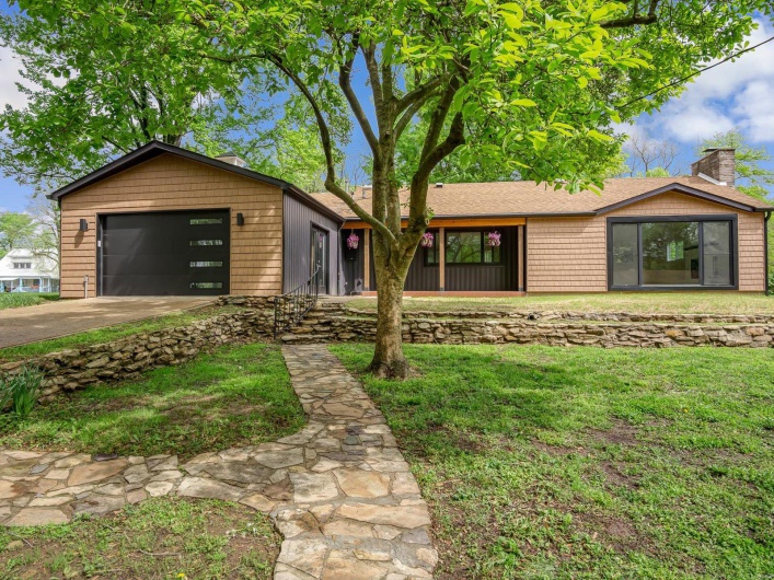 View of front facade with driveway, a chimney, roof with shingles, a front yard, and a garage