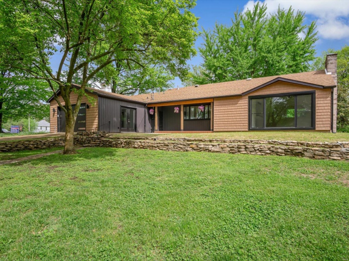 Back of house with a yard, an attached garage, and a chimney