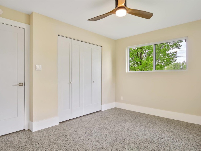 Unfurnished bedroom with a closet, ceiling fan, speckled floor, and baseboards