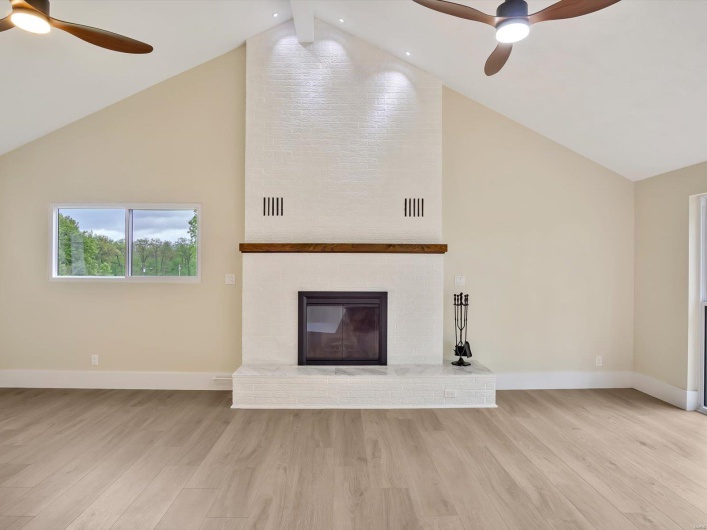 Unfurnished living room featuring baseboards, high vaulted ceiling, and a ceiling fan