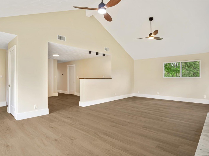 Unfurnished living room featuring ceiling fan, wood finished floors, high vaulted ceiling, and visible vents