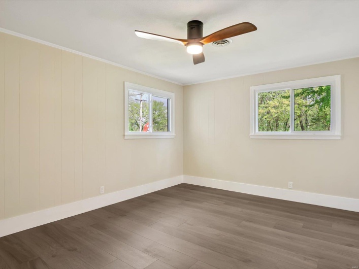 Spare room with baseboards, wood finished floors, a ceiling fan, and crown molding