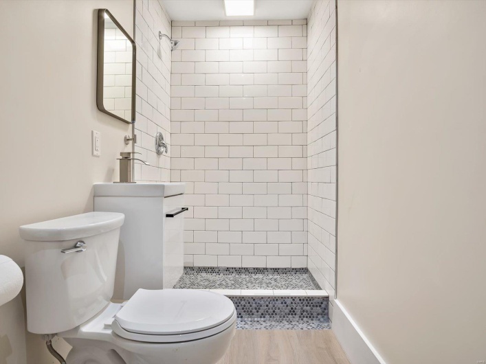 Full bathroom with a stall shower, toilet, and wood finished floors