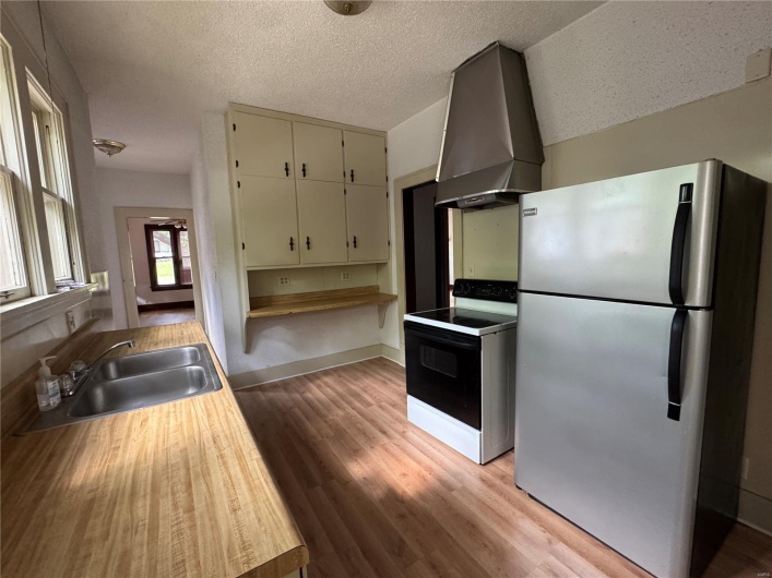 Kitchen featuring electric range, a sink, light wood-style floors, wall chimney exhaust hood, and freestanding refrigerator