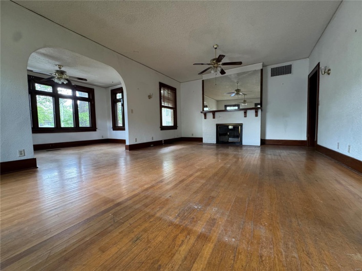 Unfurnished living room featuring a wealth of natural light, a ceiling fan, hardwood / wood-style flooring, and visible vents