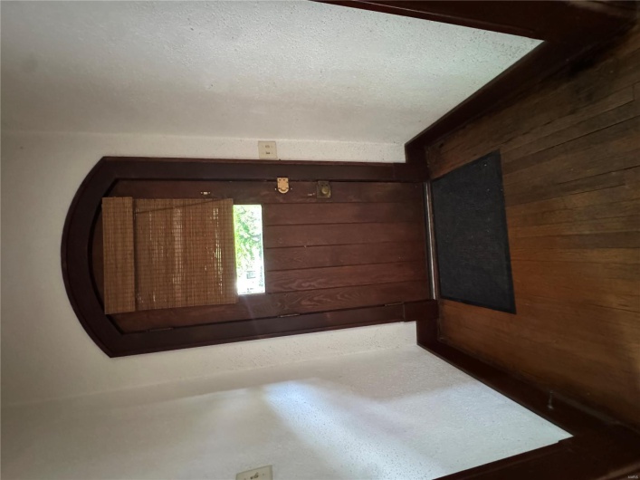 Doorway to outside featuring baseboards, arched walkways, and dark wood finished floors