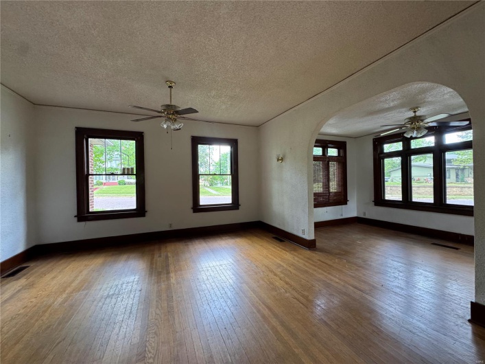 Unfurnished room with wood-type flooring, a ceiling fan, and arched walkways