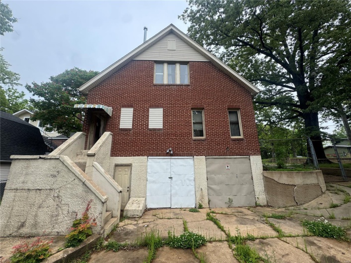 Back of house with an attached garage and brick siding