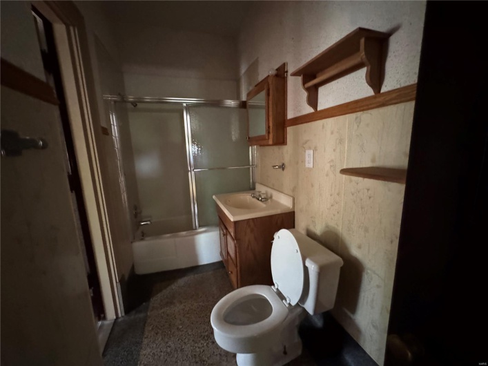 Full bath with vanity, bath / shower combo with glass door, and toilet