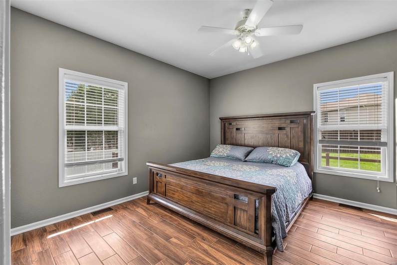 Bedroom with baseboards, a ceiling fan, wood finished floors, and visible vents