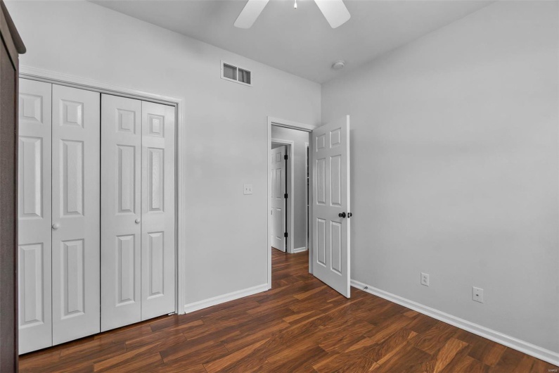 Unfurnished bedroom with a closet, baseboards, visible vents, and dark wood-type flooring