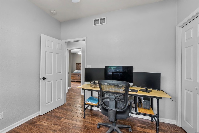 Office space featuring baseboards, visible vents, and wood finished floors