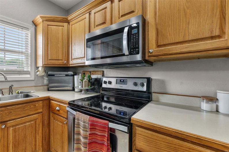 Kitchen featuring light countertops, stainless steel appliances, brown cabinets, and a sink