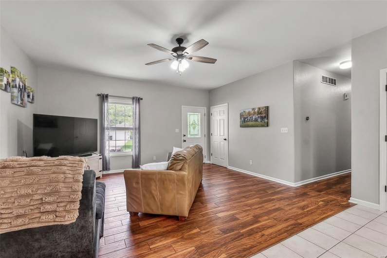 Living room with baseboards, ceiling fan, wood finished floors, and visible vents