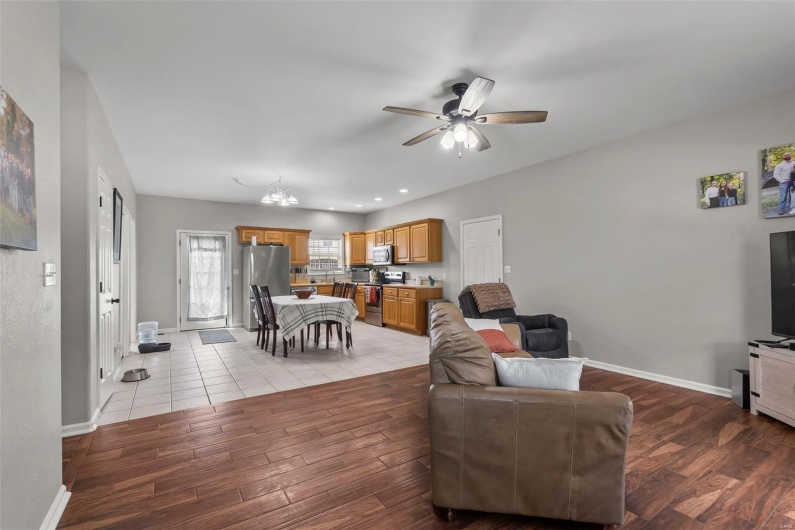Living area with baseboards, ceiling fan with notable chandelier, recessed lighting, and light wood-style flooring