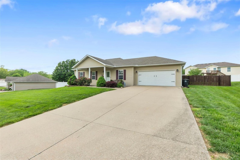 Ranch-style house with concrete driveway, an attached garage, fence, and a front yard