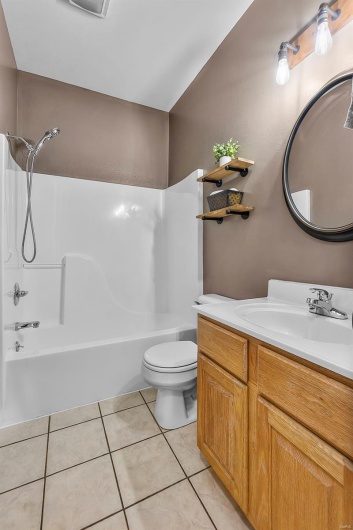 Bathroom with toilet, bathtub / shower combination, tile patterned flooring, and vanity