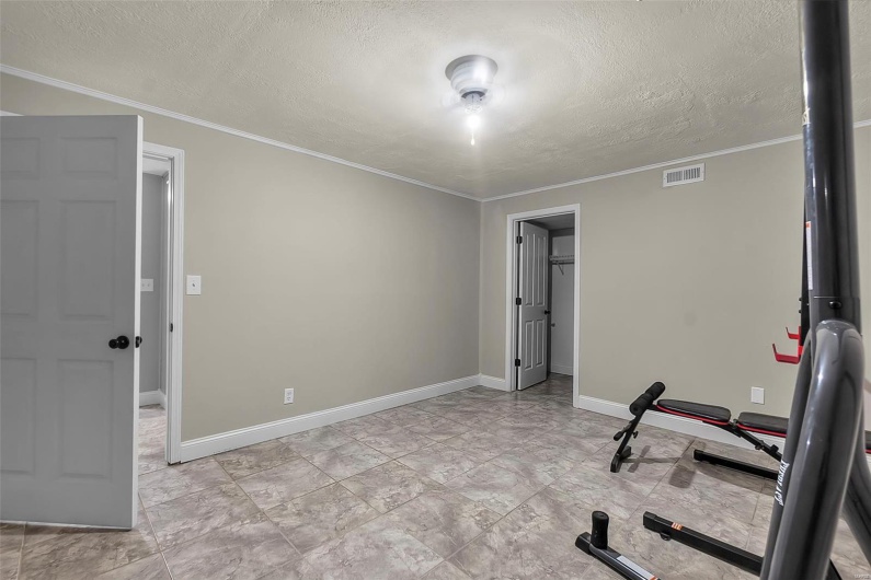 Exercise area featuring visible vents, a textured ceiling, crown molding, and baseboards