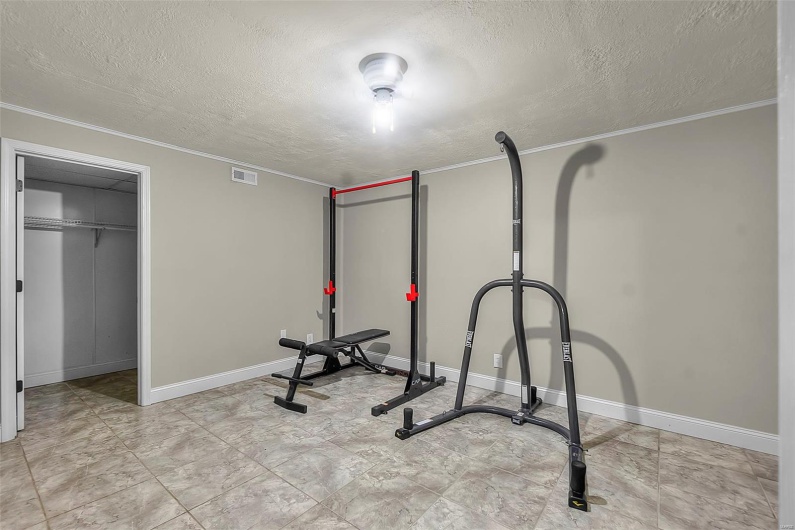 Exercise area featuring crown molding, a textured ceiling, and visible vents