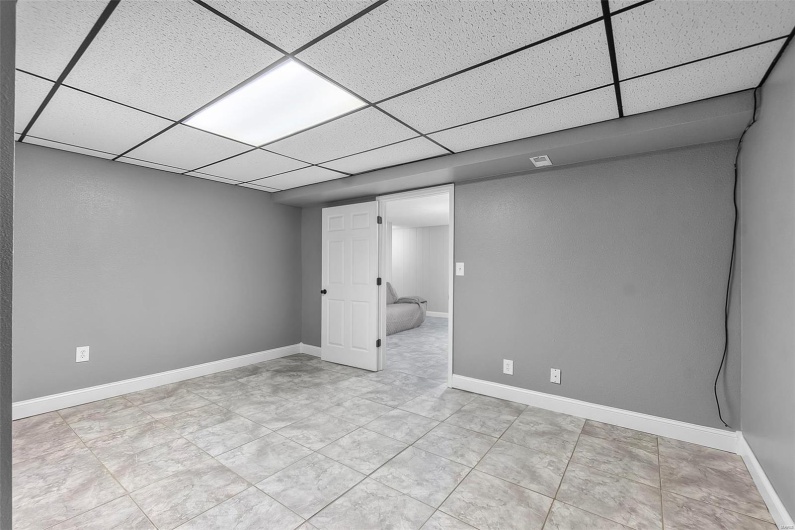 Finished basement featuring baseboards, a drop ceiling, and visible vents