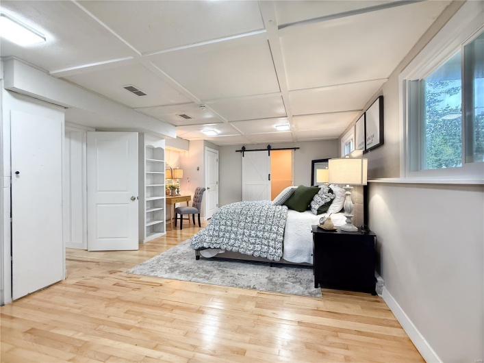 Bedroom with visible vents, a barn door, baseboards, and light wood-style floors